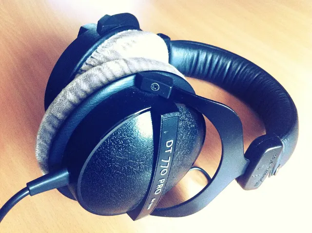 beyerdynamic DT 770 PRO 80 ohm headphones with grey velour pads lying on a wooden desk
